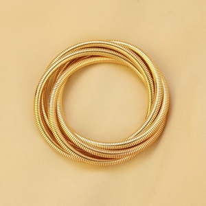 Detailed macro view of gold multi-layer spiral snake bone textured bracelet on satin