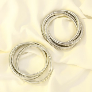 Close-up of silver-toned coiled multi-layer elastic bracelets on silk fabric