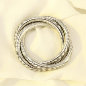 Detail shot of a silver multi-layered snake chain wrap bracelet on beige fabric