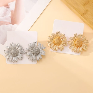 Detail of gold and silver daisy earrings with multi-layered petals on white card