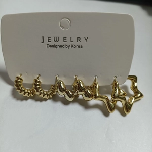 Detail von 3-teiligem goldenem Legierungs-Ohrring-Set mit Spiral- und Geometrieformen auf Karte
