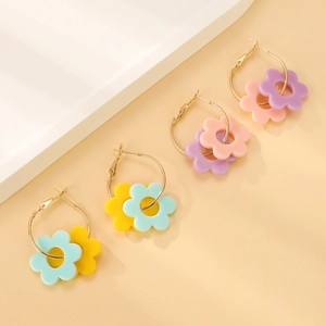Nahaufnahme von pastellfarbenen Acryl-Blumenanhängern an goldenen Creolen im Set