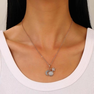 Detail van zilveren zon maan en ster hanger ketting met blauwe kristallen op model