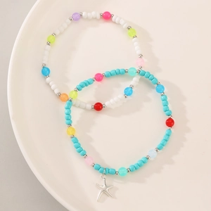Detalle de cuentas de colores y dijes de estrella de mar en tobilleras elásticas boho