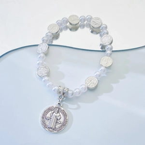 Détail macro de la médaille de Saint Benoît et des perles blanches sur le bracelet rosaire