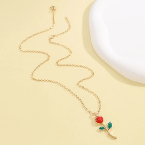 Détail du pendentif rose en émail rouge avec feuilles vertes sur une fine chaîne dorée