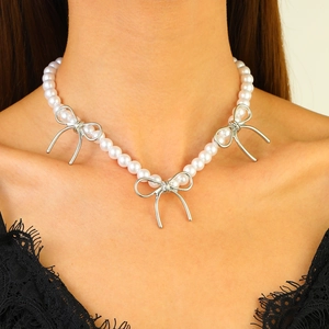 Gros plan sur un collier de perles double couche élégant avec breloques nœuds argentés