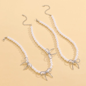 Vue détaillée des colliers de perles blanches avec pendentifs nœuds argentés et fermoirs
