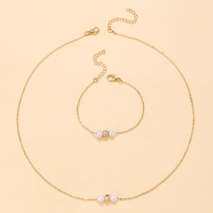 Vista dettagliata del set collana e bracciale dorati con perle e perline metalliche