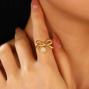 Nahaufnahme eines goldenen Schleifenrings mit kleiner weißer Perle am Finger des Models