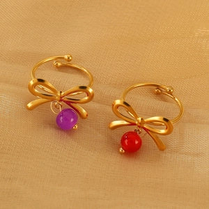 Detail von goldenen Schleifenringen mit roten und lila Perlen auf Goldseide