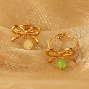 Makroaufnahme goldener Schleifenringe mit gelben und grünen Perlen auf Goldgewebe