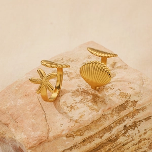 Detailed view of adjustable gold starfish and shell rings on a natural stone background