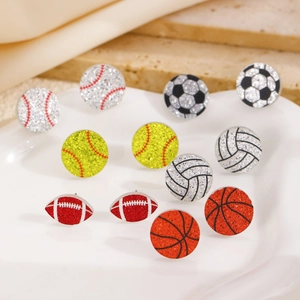 Nahaufnahme von glitzernden Sportball-Ohrsteckern in einer weißen Keramikschale