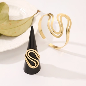 Detailed shot of gold S-curve open ring and hollow bangle with brushed metal finish