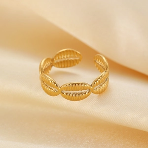 Detailed macro shot of golden adjustable ring with seashell pattern on satin fabric
