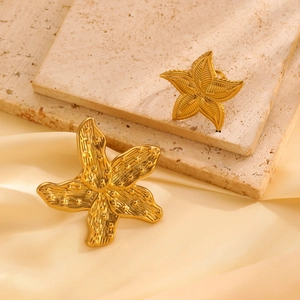 Close-up of golden starfish earrings with matte brushed metal and bead details