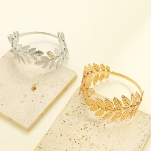 Detailed view of gold and silver laurel leaf textured bracelets on stone pedestals