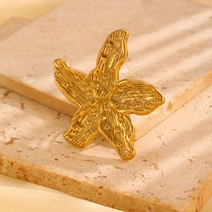 Detailed close-up of golden starfish ring with realistic textured relief on stone base