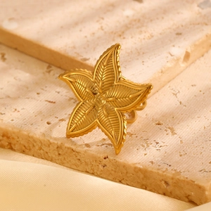 Macro shot of gold starfish ring featuring textured details on a beige travertine base
