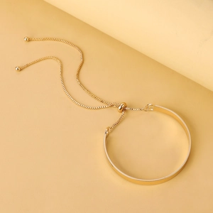 Detail of adjustable gold S-shaped bracelet with slider chain and polished finish