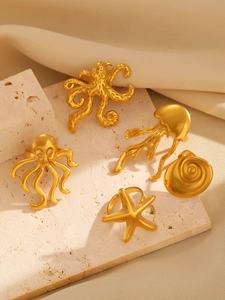 Detailed view of five-piece gold starfish and octopus sea creature rings on marble