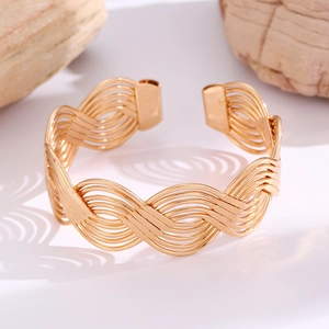 Detailed close-up of golden dual-layer S-shaped open bracelet with braided hollow texture