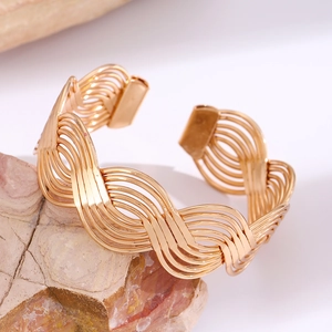 Detail of gold open cuff bracelet with wavy multi-layered hollow weaving design