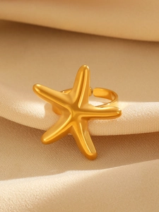 Macro shot of polished gold starfish ring on silk fabric with open adjustable design