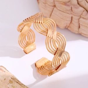 Detail of gold double-layer S-shape open cuff bracelet with woven texture on white stones