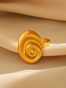 Macro detail of golden oval ring with spiral sea snail texture on champagne satin