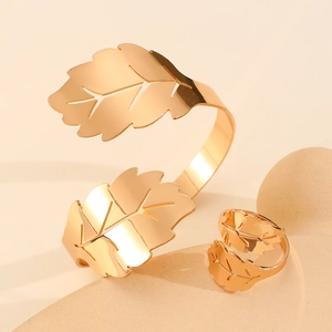 Minimalist golden leaf open bangle and matching ring set on aesthetic display
