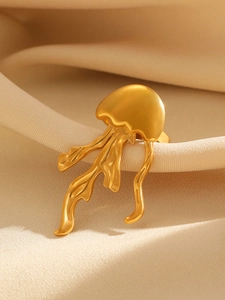Macro detail of gold jellyfish ring showcasing fluid tentacles on beige satin background