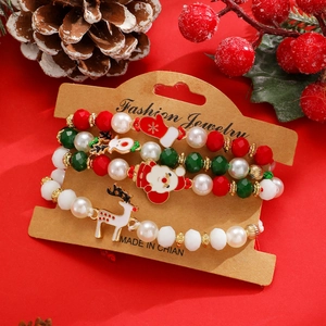 Macro di set di braccialetti natalizi con ciondoli Babbo Natale su sfondo rosso festivo