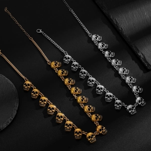Nahaufnahme von Punk-Schädel-Halsketten in Gold und Silber auf schwarzem Steinhintergrund