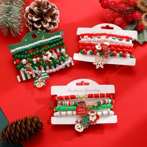 Dettaglio di braccialetti natalizi multistrato con ciondoli Babbo Natale e fiocchi di neve