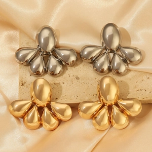 Polished gold and silver metal teardrop stud earrings displayed on elegant silk fabric