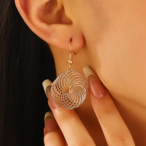 Detailed close-up of golden spiral hollow earrings with elegant wire texture on model