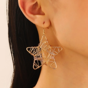 Close-up of a model wearing large golden wire-wrapped star earrings with fish hooks