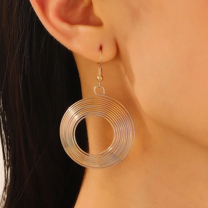Detailed view of layered golden geometric wire wrap round earrings on a model