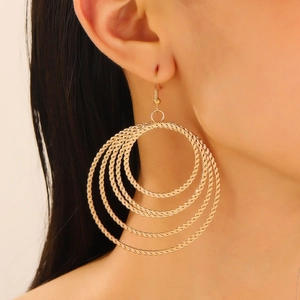 Close-up of golden multi-layer hoop earrings with textured weave design on a model