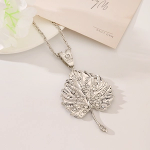 Detalle de collar con colgante de hoja plateada con pedrería y cadena de cordón trenzado