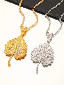 Detalle macro de colgantes de hoja en oro y plata con pedrería en cadenas de cuerda