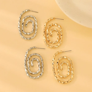 Detail of geometric spiral hoop earrings in gold and silver with textured facets
