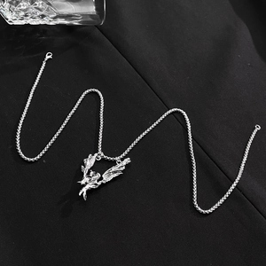 Detail of silver angel pendant with vintage finish and box chain on black fabric