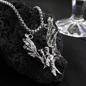 Detailed view of silver skull angel pendant with box chain on volcanic rock texture