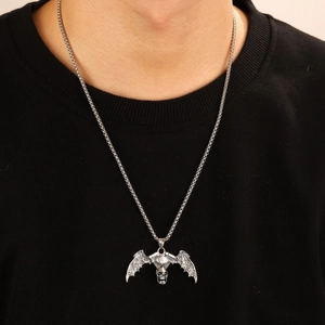 Detail of retro silver skull and bat wing engine pendant on a metal link chain