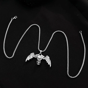 Macro detail of silver gothic skull bat pendant with vintage distressed finish and chain
