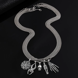 Detail of multi-layer gothic necklace with skeleton, spider and web charms on black background