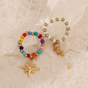 Detail of beaded rings set featuring a gold star and seahorse charms on lace
